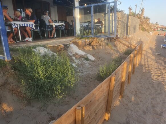 Foto gemaakt door Reinout van den Born - Las Chapas Playa - De deuren van restaurant las Flores hangen boven het afgeslagen zand. Een provisorisch geplaatst wandje moet voorlopig even erger voorkomen. 